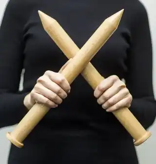 Hands working with chunky knitting needles and natural white wool
