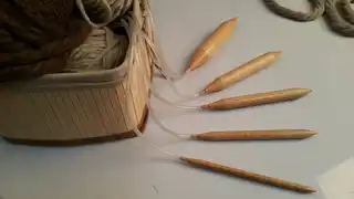 Hands working on a traditional wooden loom with natural wool