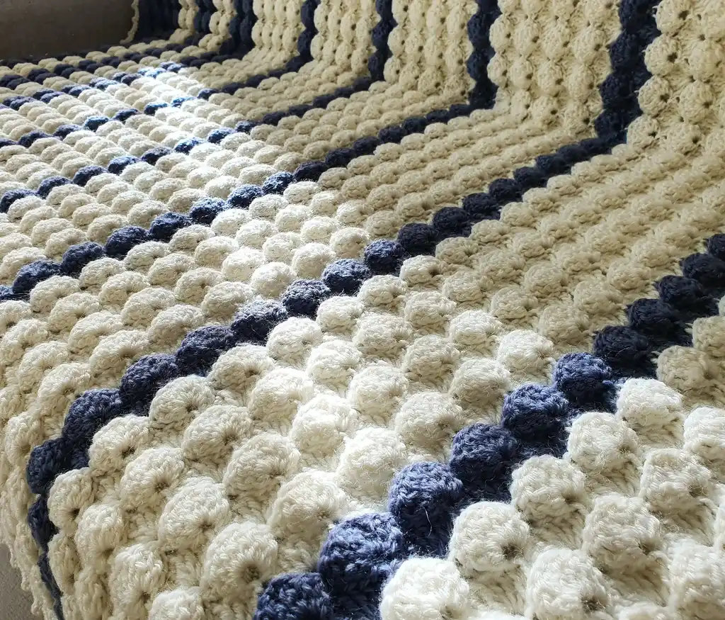 handmade crochet throw blanket in blended wool with intricate patterns.