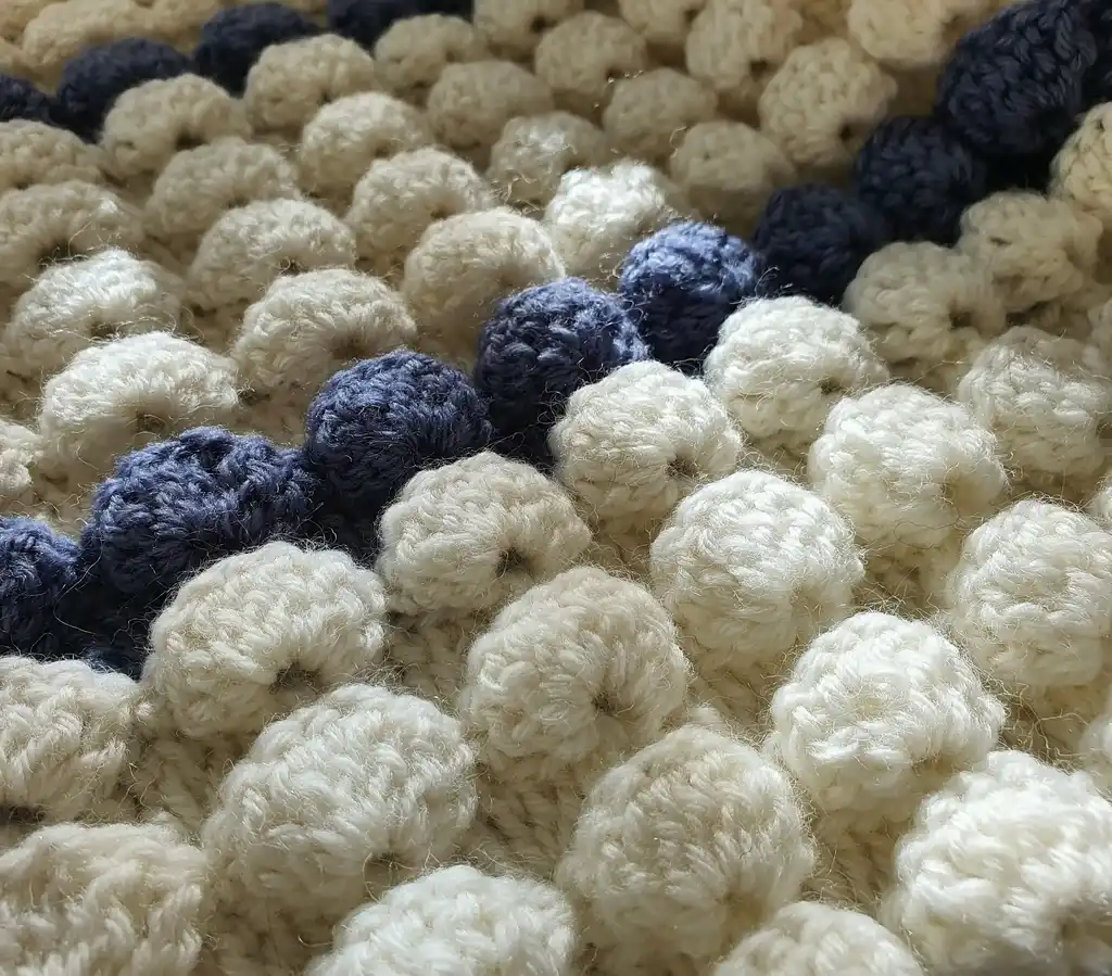 handmade crochet throw blanket in blended wool with intricate patterns.