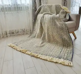 Handmade chunky merino wool crochet blanket in neutral tones.