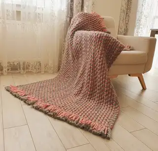 handcrafted crochet blanket made from chunky merino wool in neutral colors.