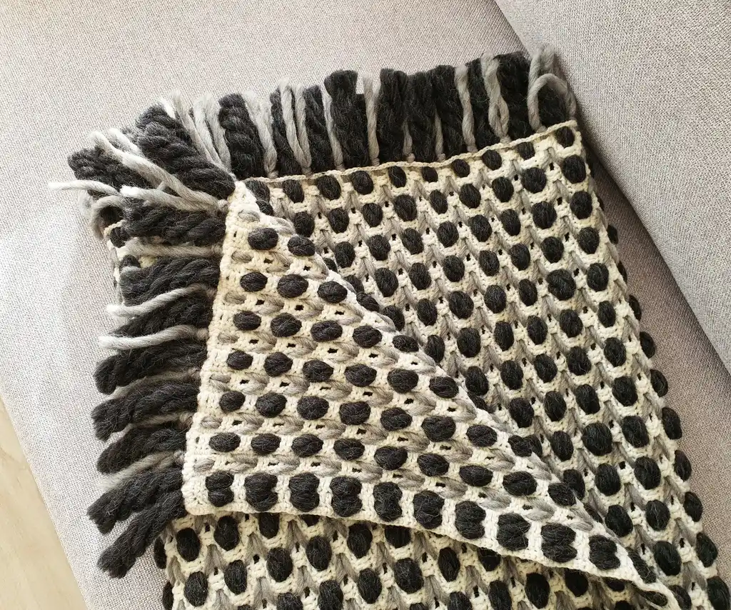 Handmade crochet blanket in chunky merino wool with textured pattern.