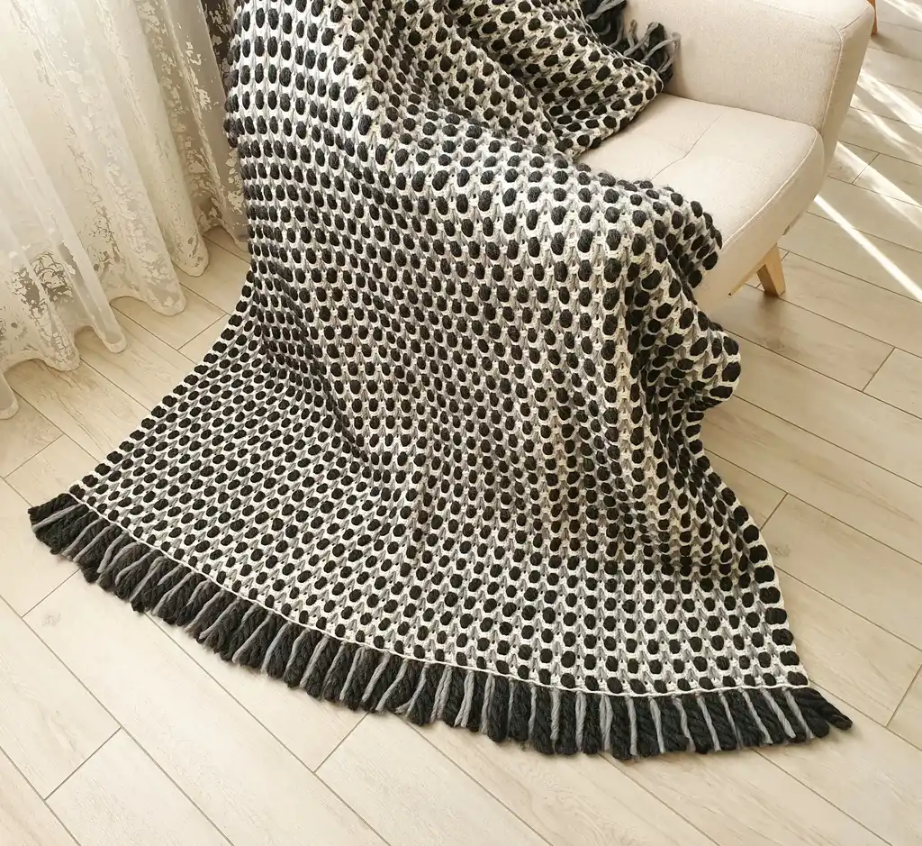 Handmade crochet blanket in chunky merino wool with textured pattern.