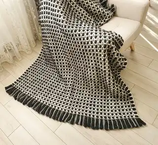 Handmade crochet blanket in chunky merino wool with textured pattern.