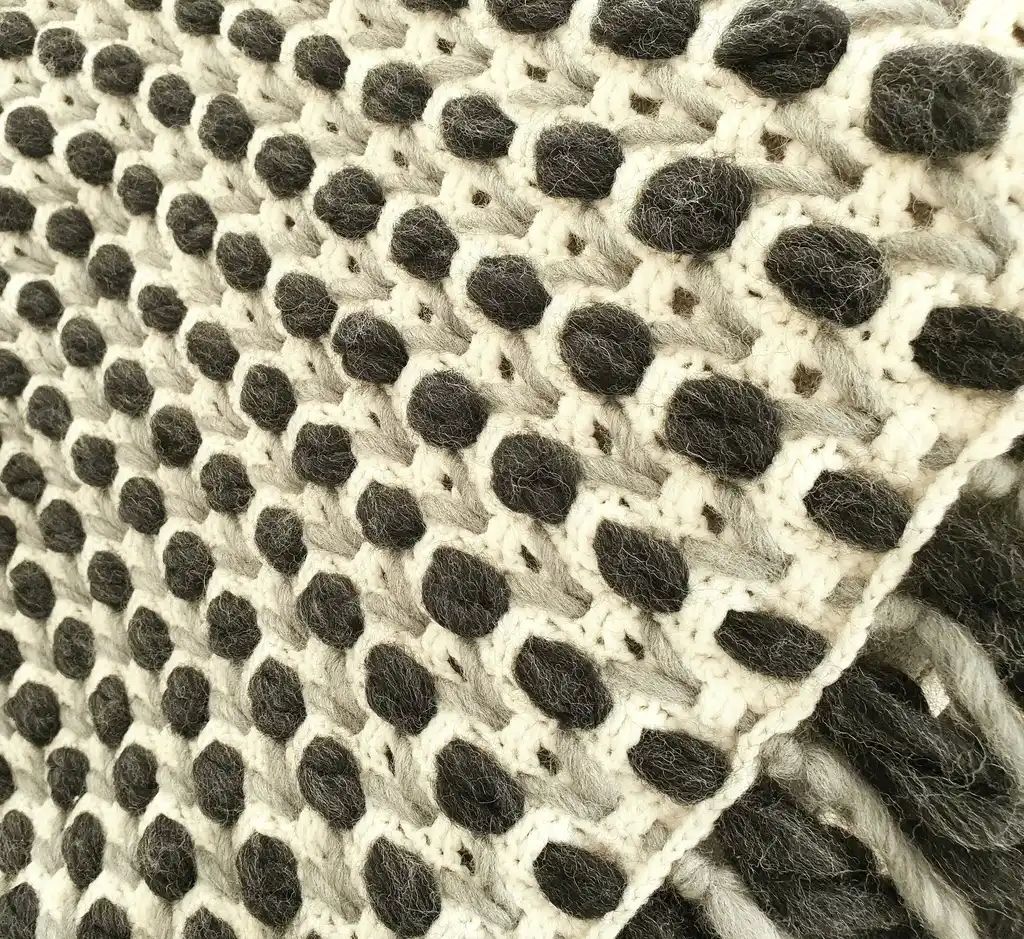 Handmade crochet blanket in chunky merino wool with textured pattern.