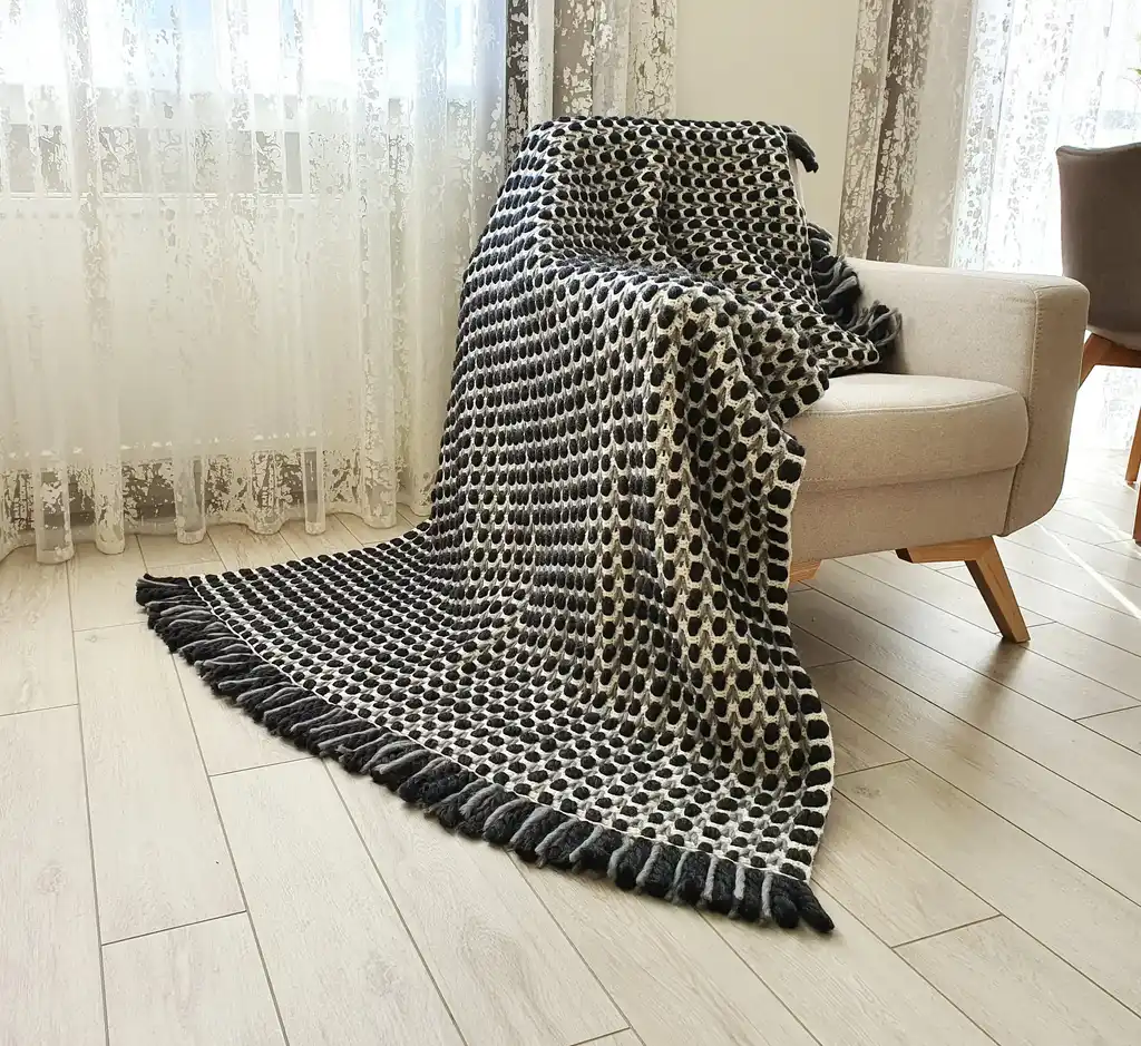 Handmade crochet blanket in chunky merino wool with textured pattern.