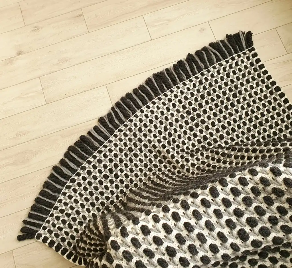 Handmade crochet blanket in chunky merino wool with textured pattern.