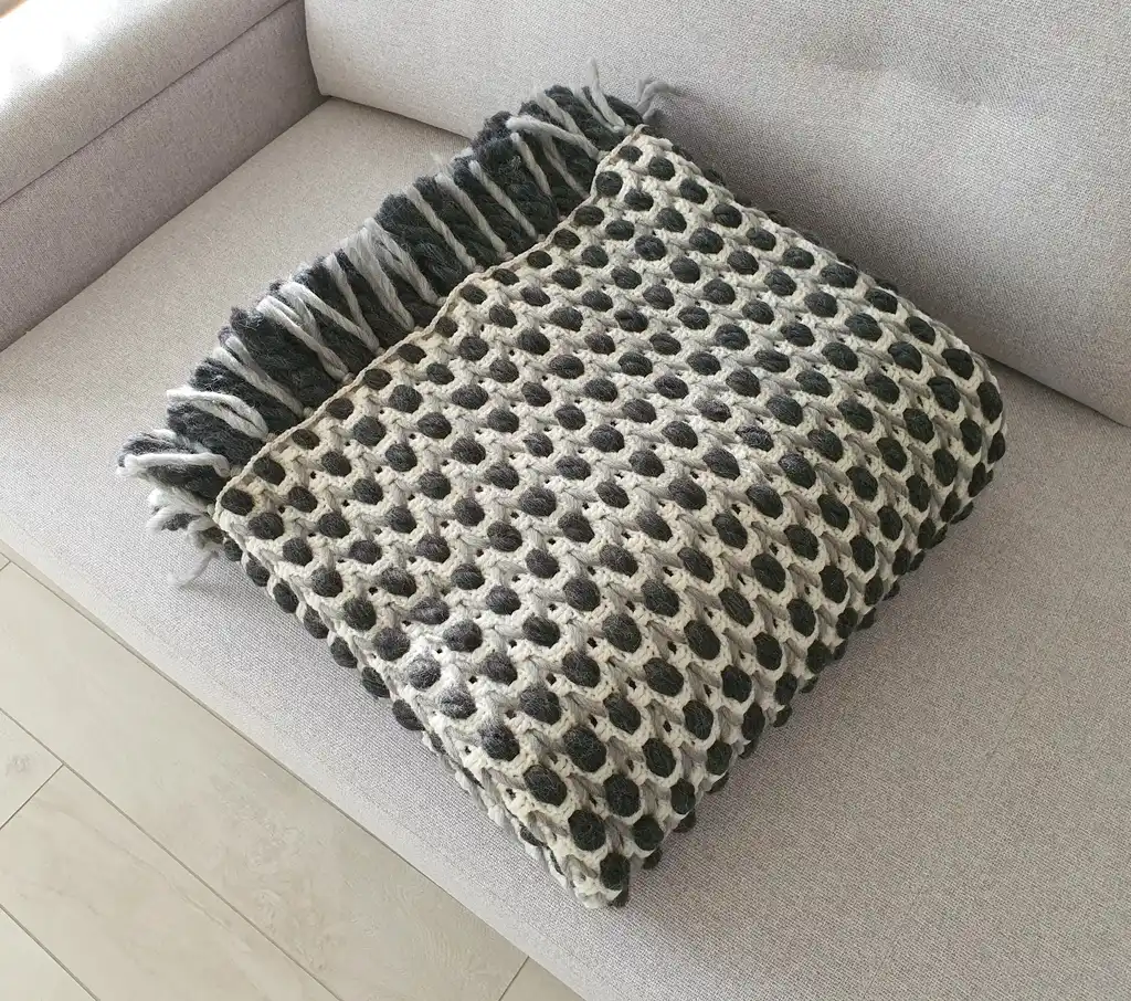 Handmade crochet blanket in chunky merino wool with textured pattern.
