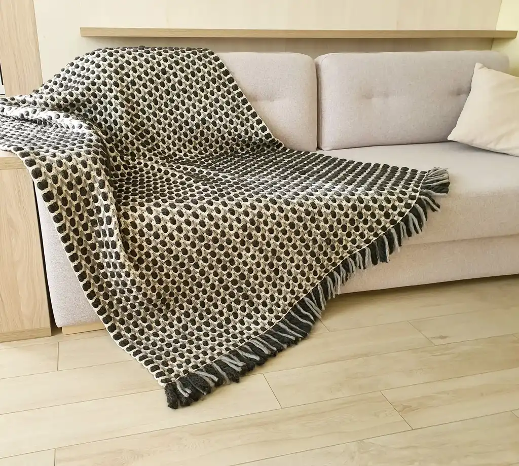 Handmade crochet blanket in chunky merino wool with textured pattern.