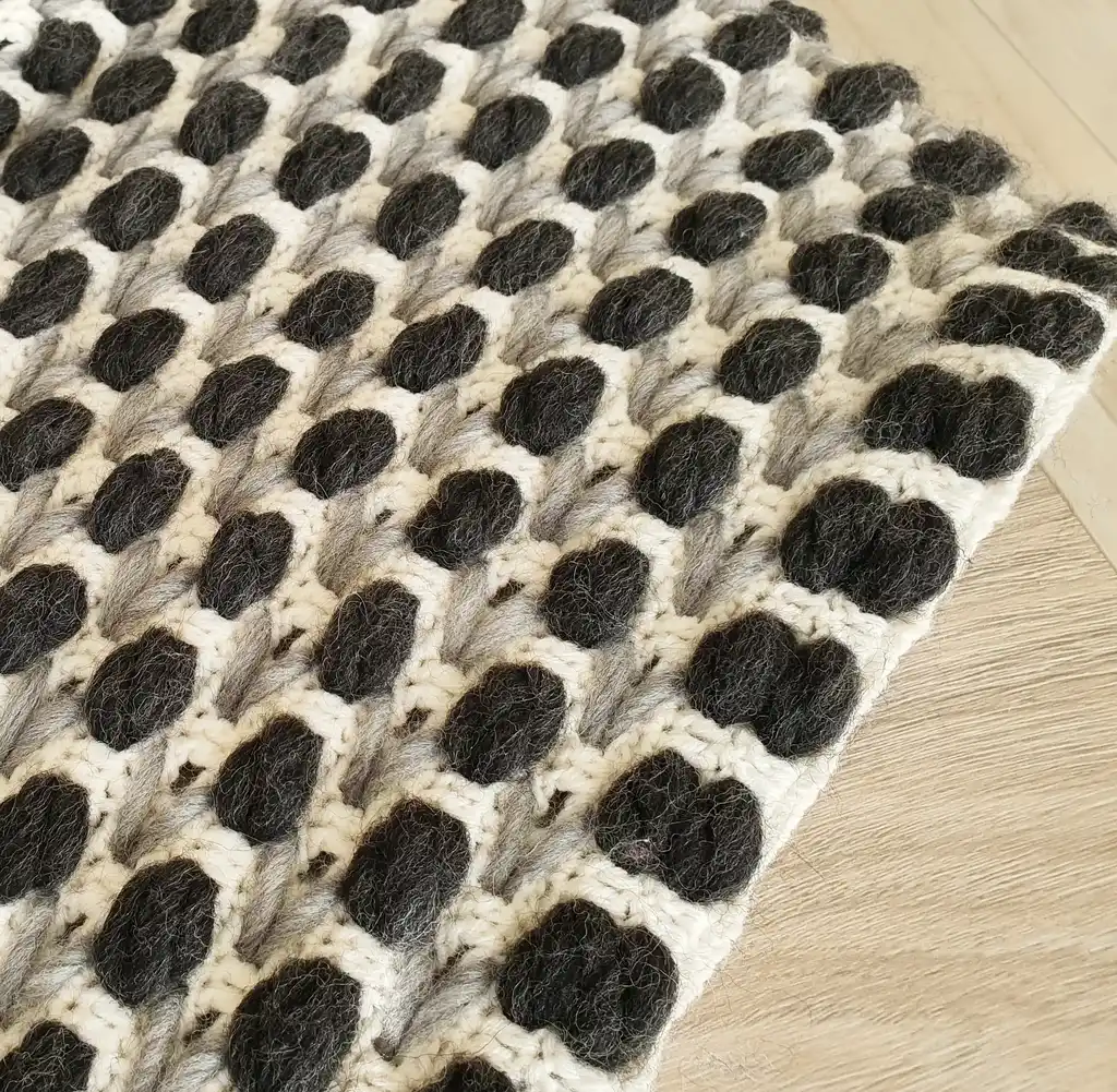 Handmade crochet blanket in chunky merino wool with textured pattern.