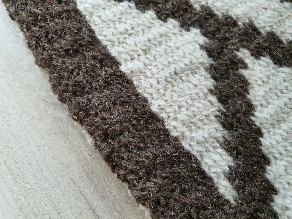 Crochet wool rug in natural colors, showing detailed texture and craftsmanship.