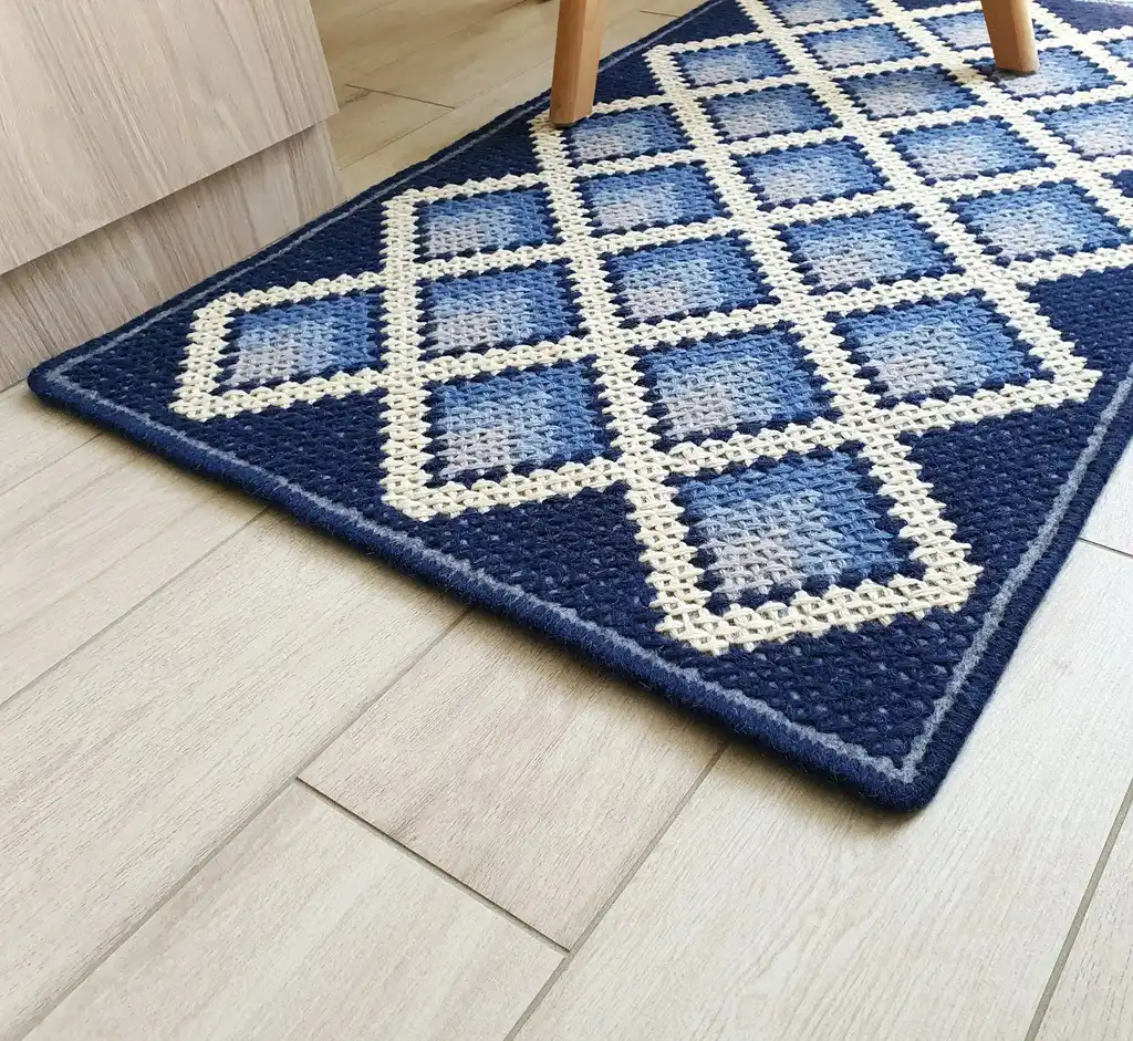 handcrafted cross-stitch wool rug on felt base with traditional patterns.