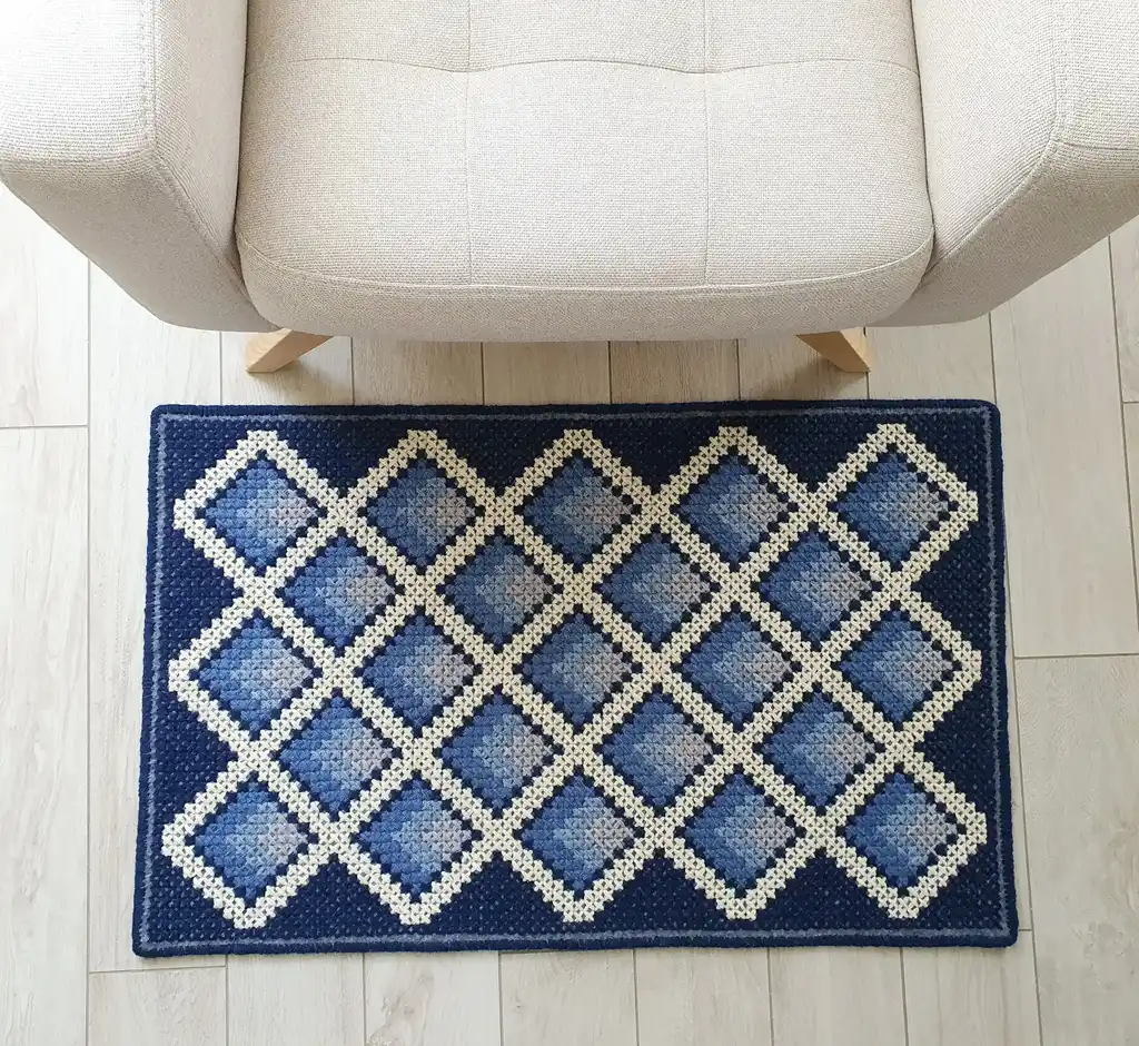 handcrafted cross-stitch wool rug on felt base with traditional patterns.