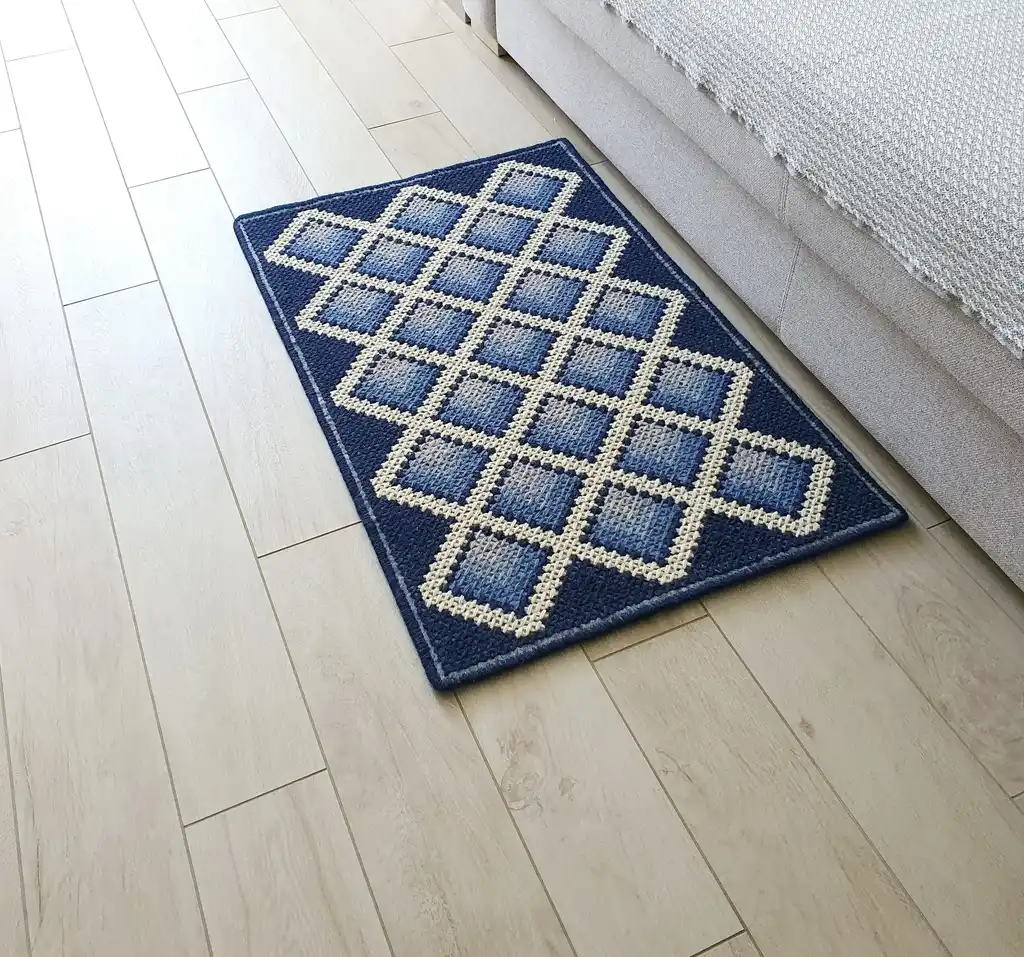 handcrafted cross-stitch wool rug on felt base with traditional patterns.