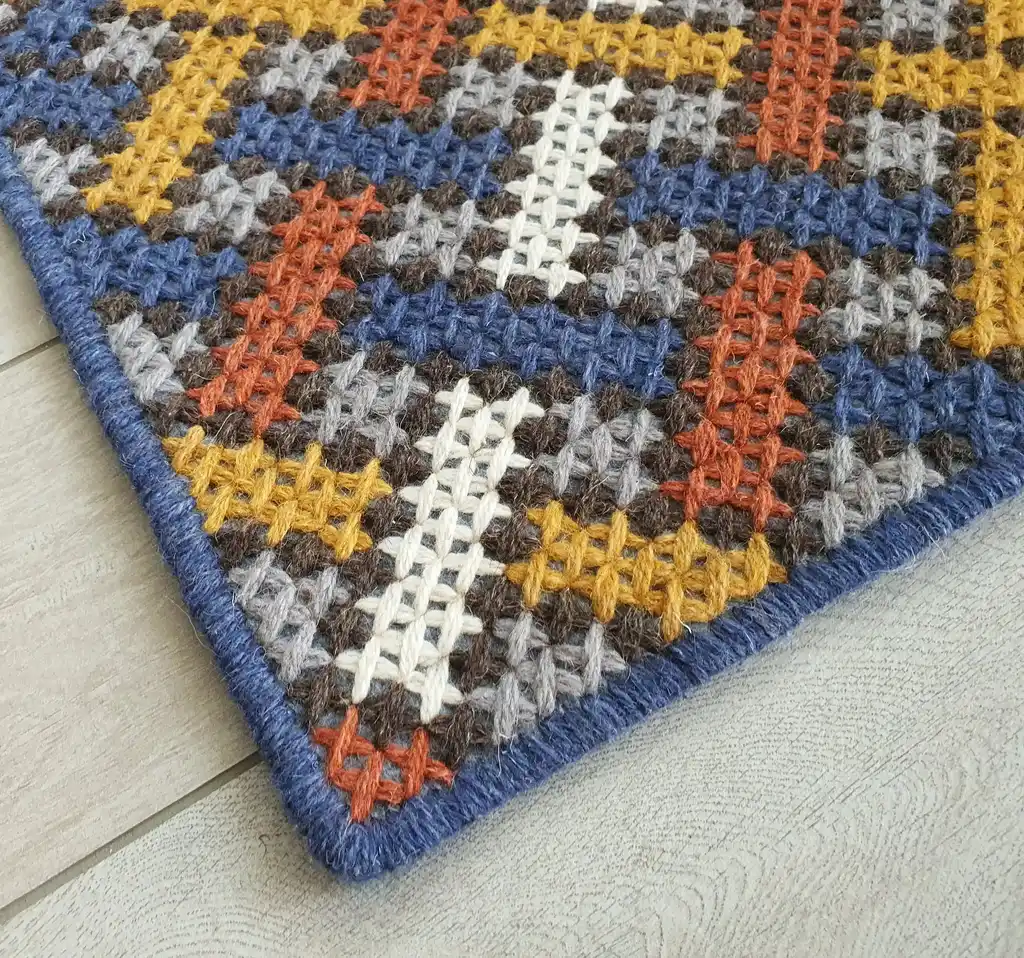 Handcrafted cross-stitch rug made from wool and felt, showcasing intricate embroidery patterns.