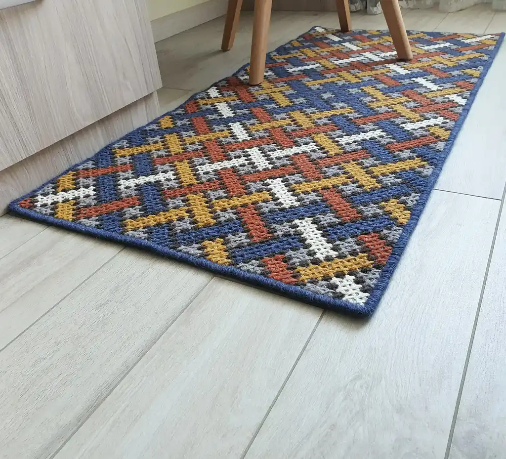 Handcrafted cross-stitch rug made from wool and felt, showcasing intricate embroidery patterns.