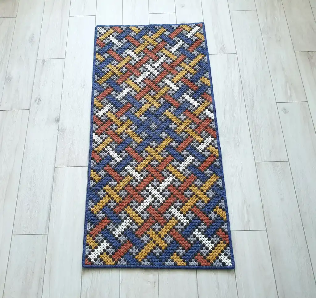 Handcrafted cross-stitch rug made from wool and felt, showcasing intricate embroidery patterns.