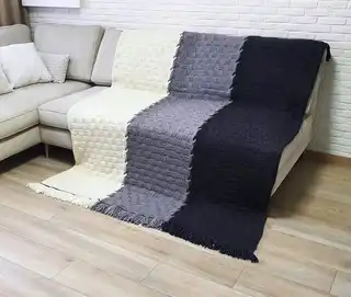 luxury merino wool knitted throw blanket in natural color, showing soft texture and quality craftsmanship.