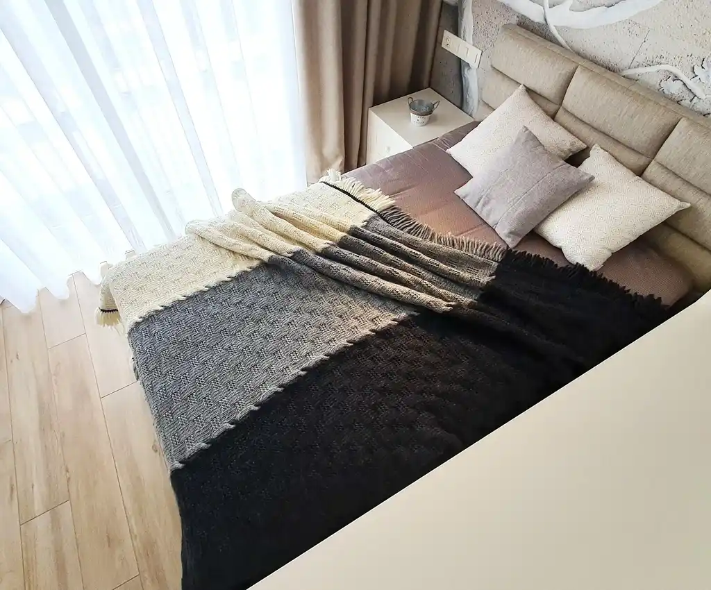 luxury merino wool knitted throw blanket in natural color, showing soft texture and quality craftsmanship.