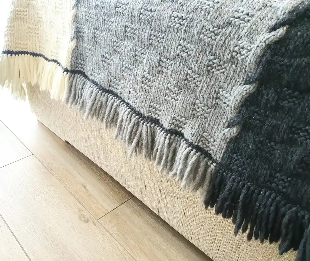 luxury merino wool knitted throw blanket in natural color, showing soft texture and quality craftsmanship.