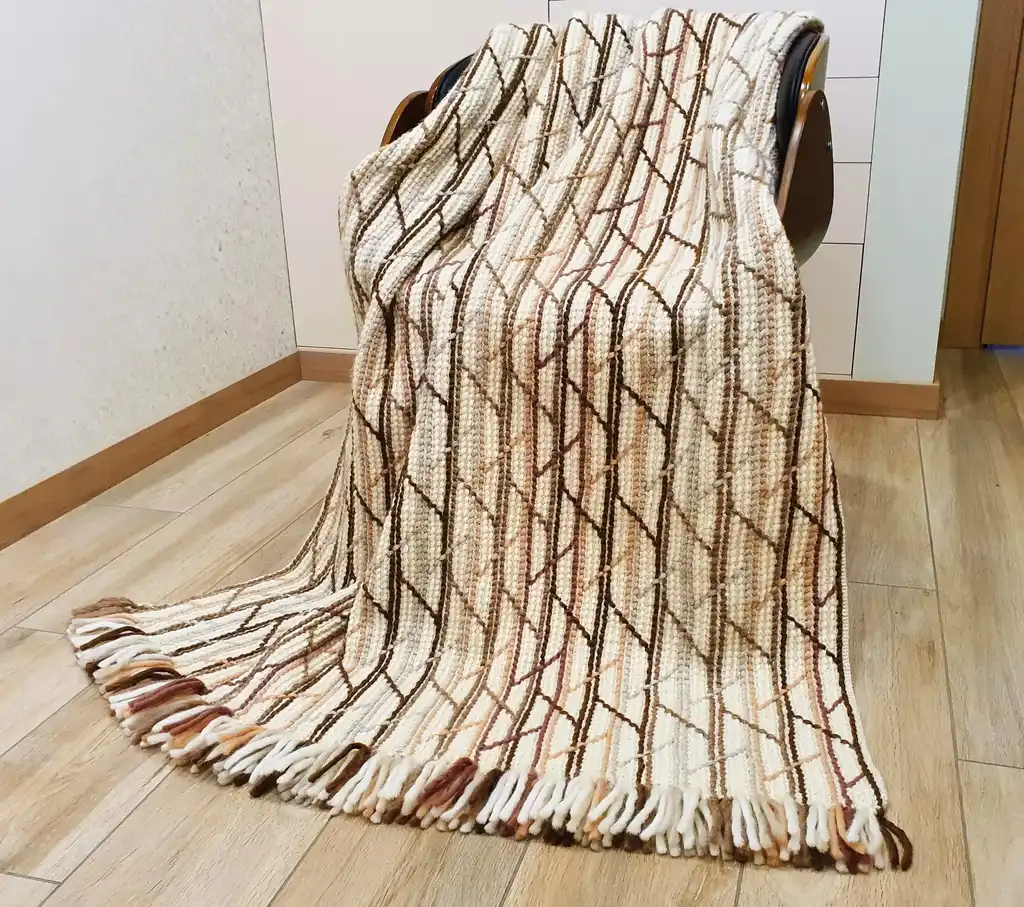 Handmade crochet blanket in merino wool with intricate patterns.