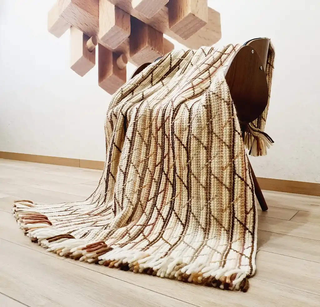 Handmade crochet blanket in merino wool with intricate patterns.