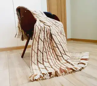 Handmade crochet blanket in merino wool with intricate patterns.