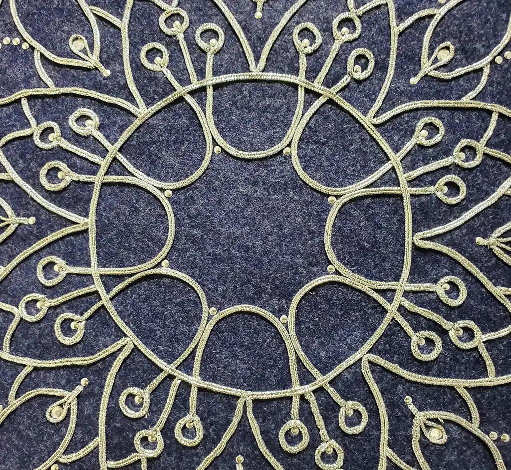 Handcrafted embroidered felt wall hanging with shimmering lurex cord decoration.
