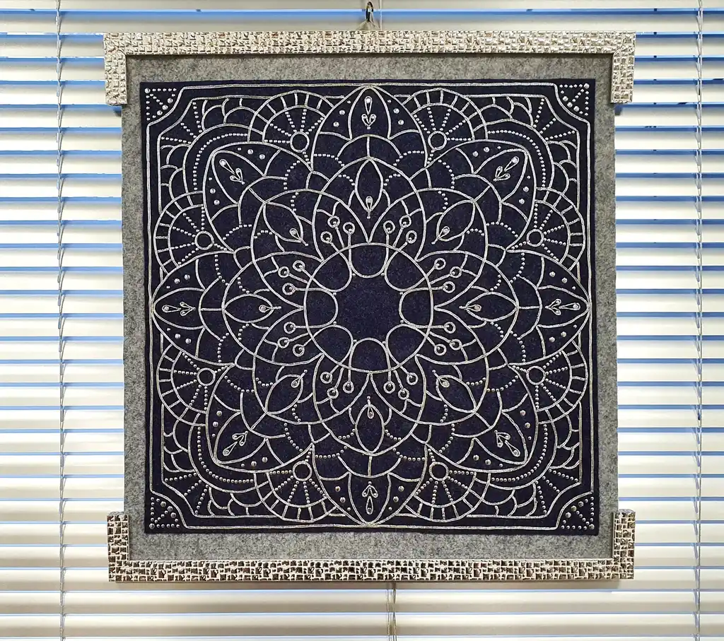 Handcrafted embroidered felt wall hanging with shimmering lurex cord decoration.