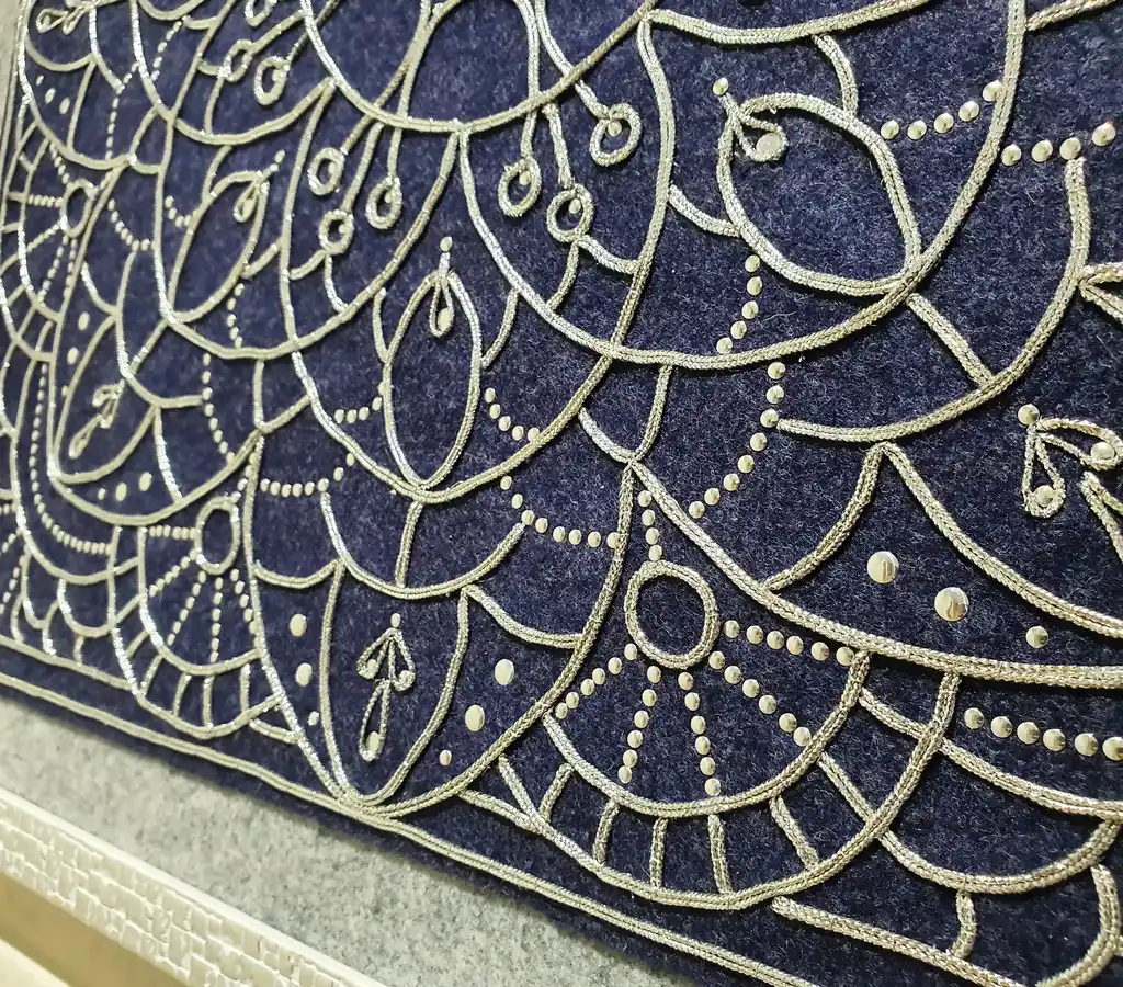 Handcrafted embroidered felt wall hanging with shimmering lurex cord decoration.