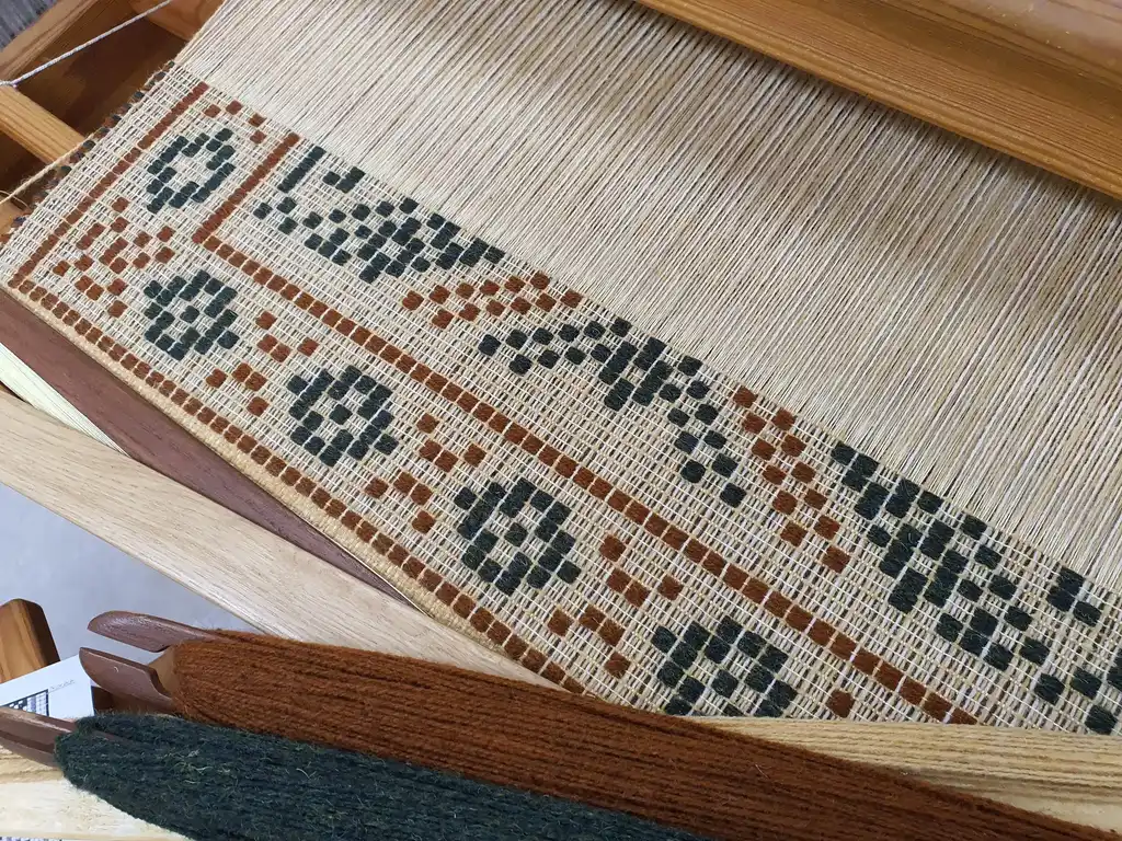 handwoven wool rug with traditional Ukrainian viburnum flower patterns in red and natural colors.