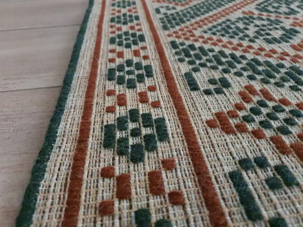 handwoven wool rug with traditional Ukrainian viburnum flower patterns in red and natural colors.