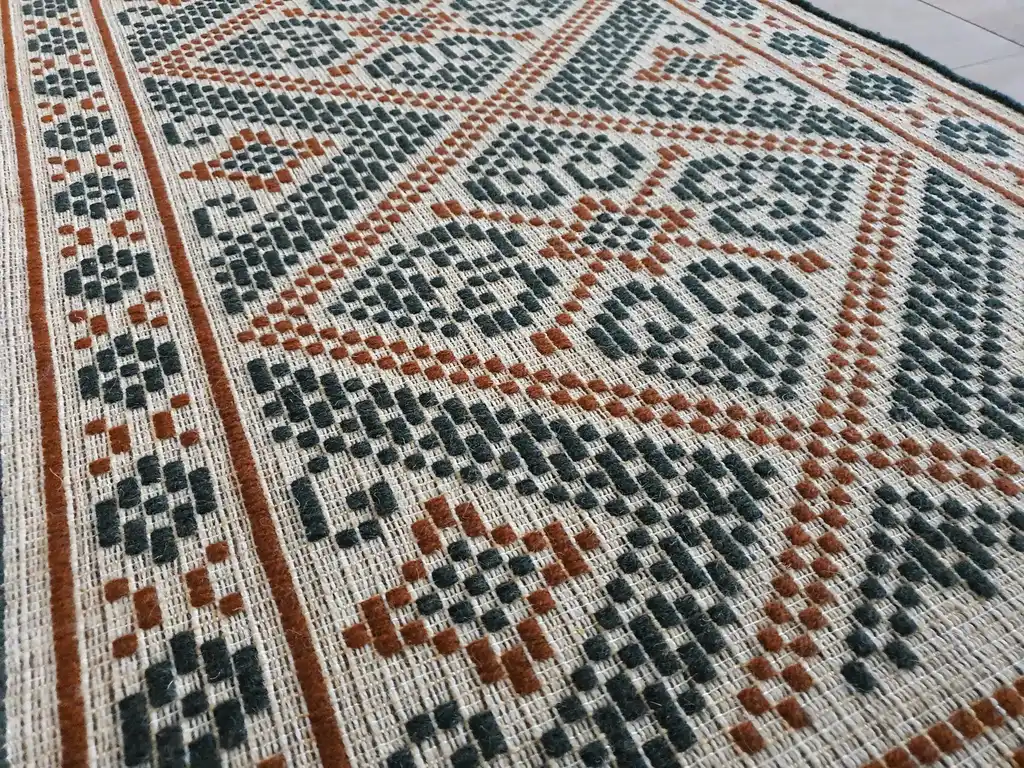 handwoven wool rug with traditional Ukrainian viburnum flower patterns in red and natural colors.