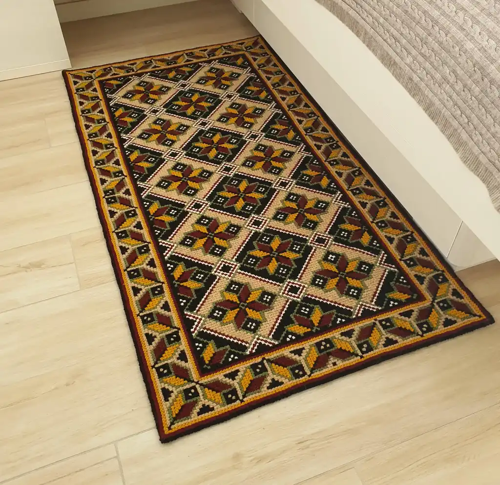Handmade cross-stitch wool rug with traditional needlework patterns.