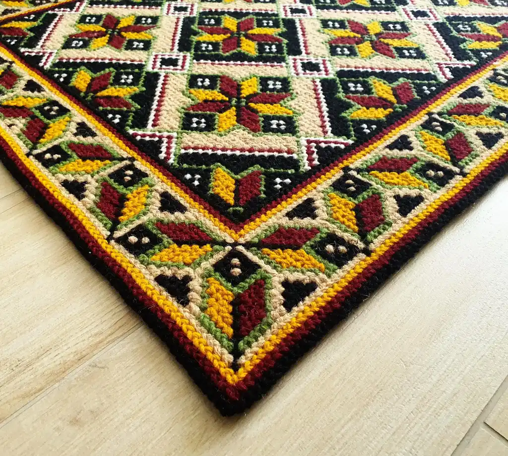 Handmade cross-stitch wool rug with traditional needlework patterns.