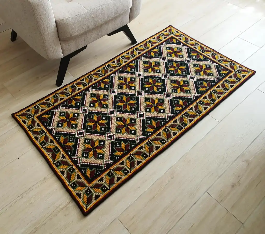Handmade cross-stitch wool rug with traditional needlework patterns.