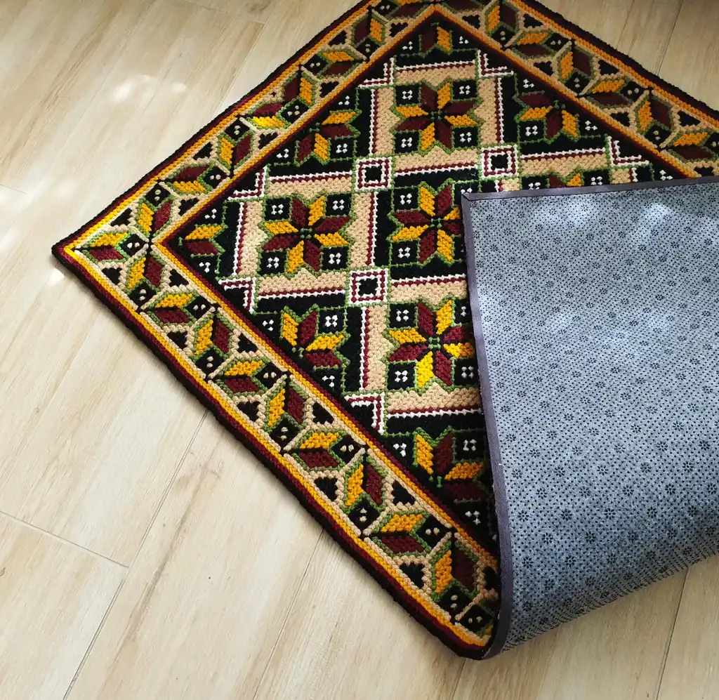 Handmade cross-stitch wool rug with traditional needlework patterns.
