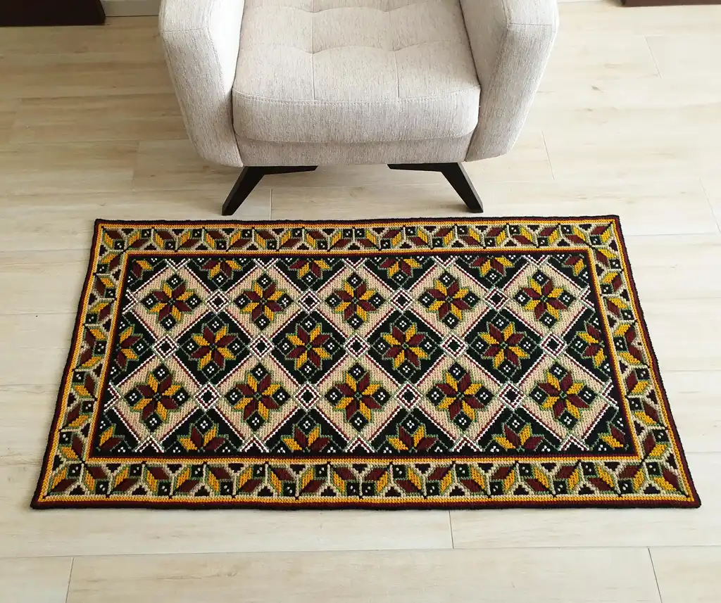 Handmade cross-stitch wool rug with traditional needlework patterns.