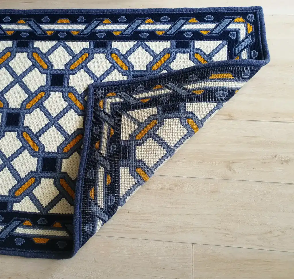 handcrafted wool rug with cross-stitch pattern.