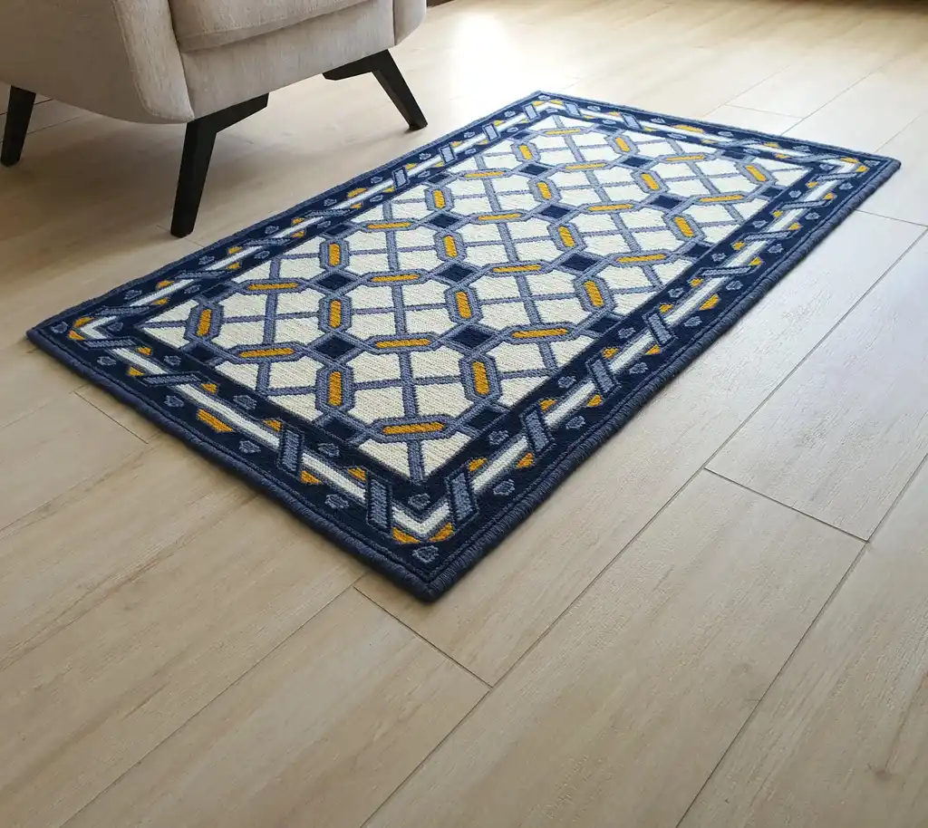 handcrafted wool rug with cross-stitch pattern.
