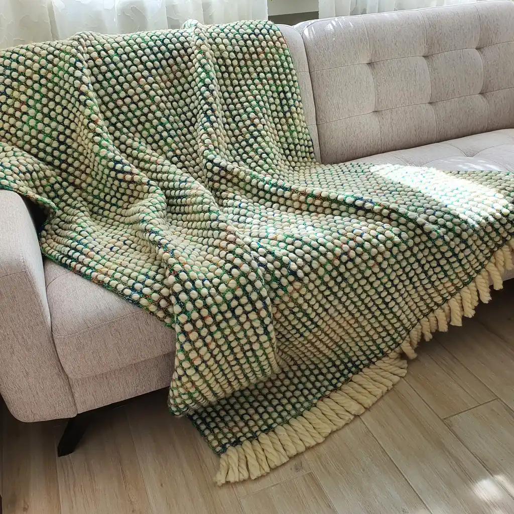 Luxurious chunky wool crochet blanket with intricate handmade patterns in neutral tones.