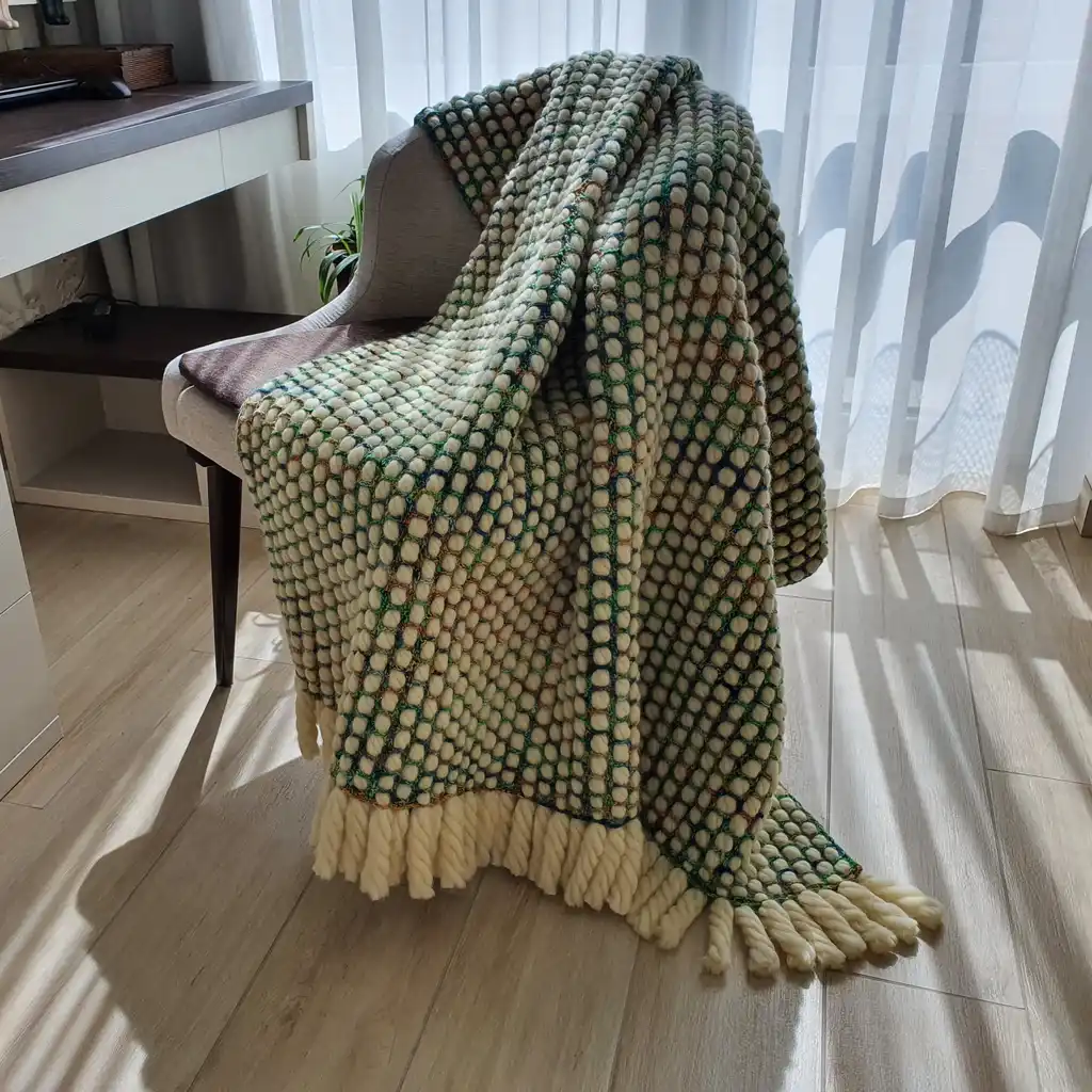 Luxurious chunky wool crochet blanket with intricate handmade patterns in neutral tones.