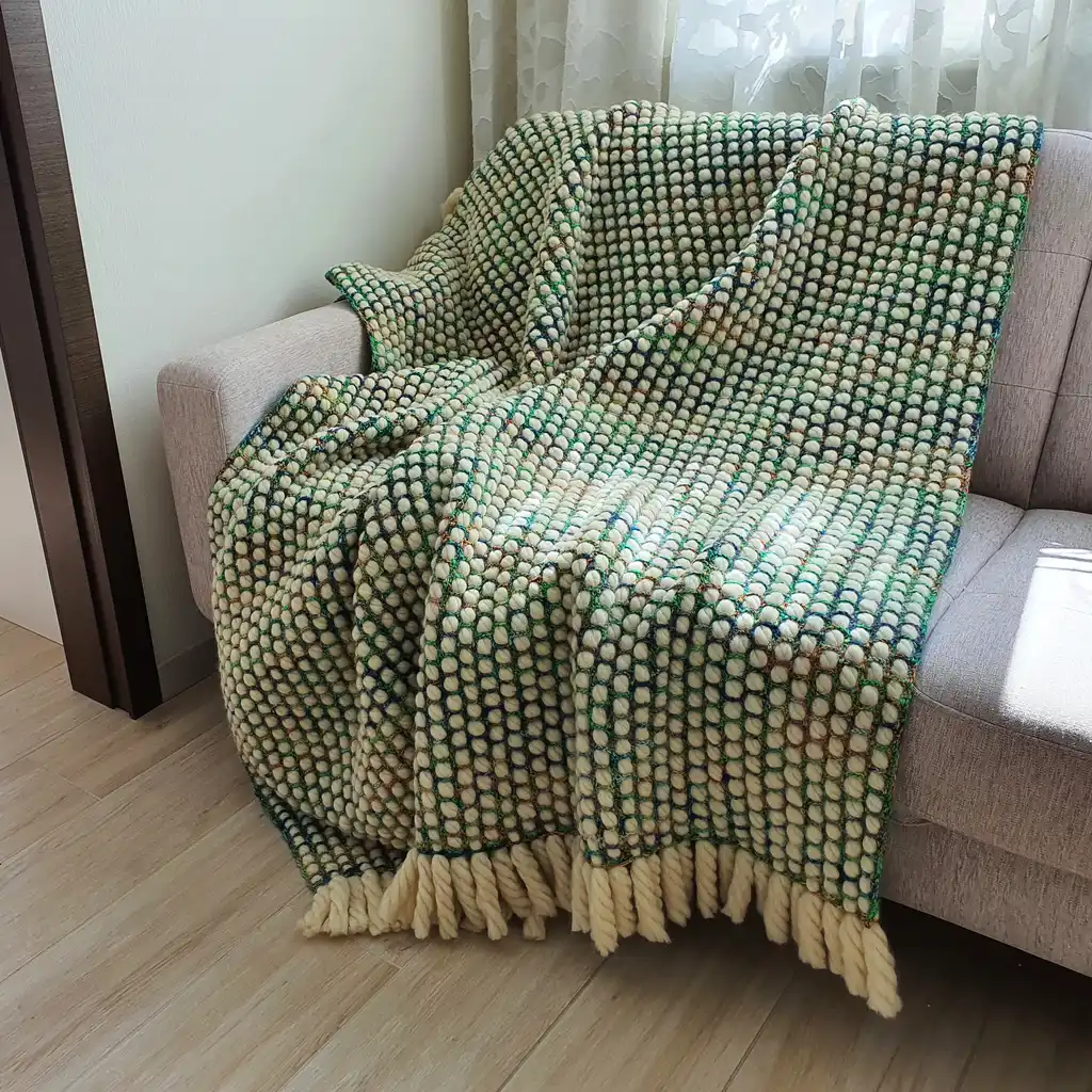 Luxurious chunky wool crochet blanket with intricate handmade patterns in neutral tones.