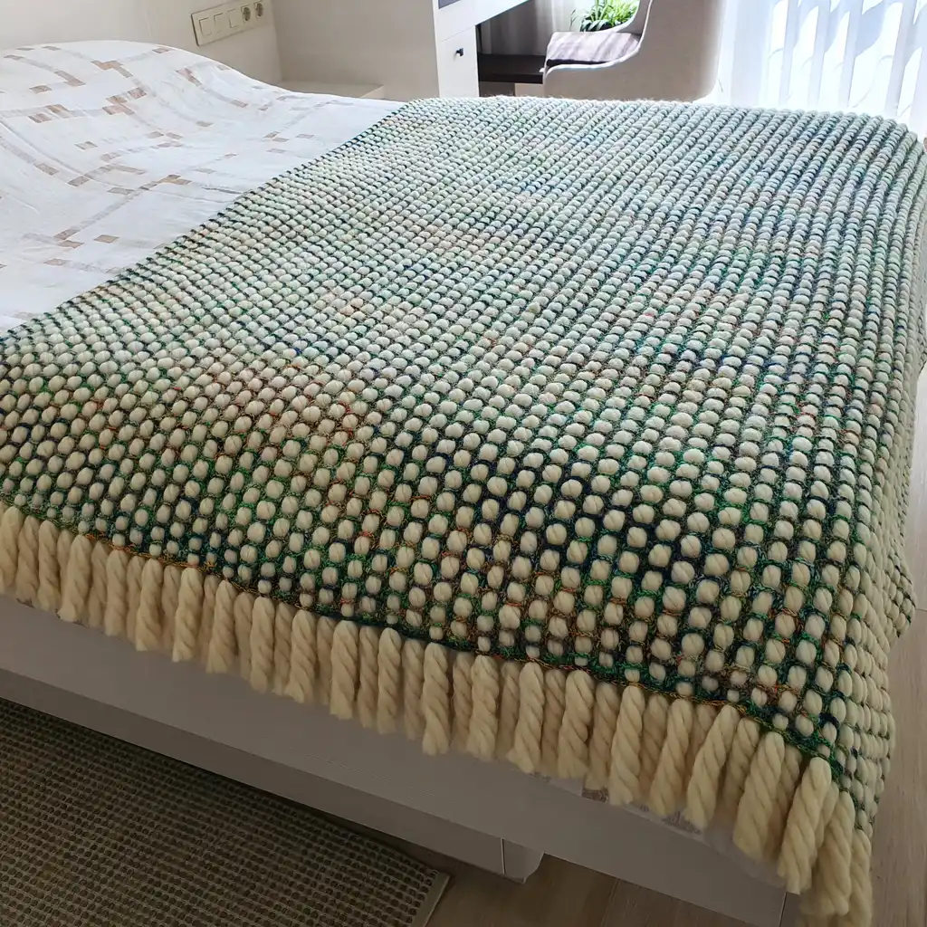 Luxurious chunky wool crochet blanket with intricate handmade patterns in neutral tones.