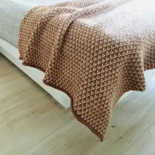 The luxury merino wool knitted throw blanket in elegant design.
