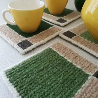 Handmade wool coasters with geometric green and brown square pattern.
