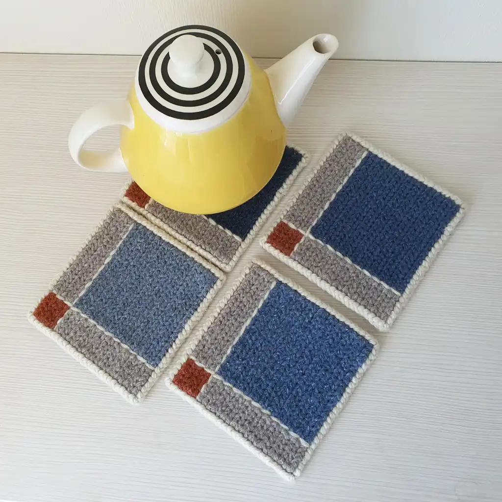 Handmade wool coasters with geometric blue and gray square pattern.