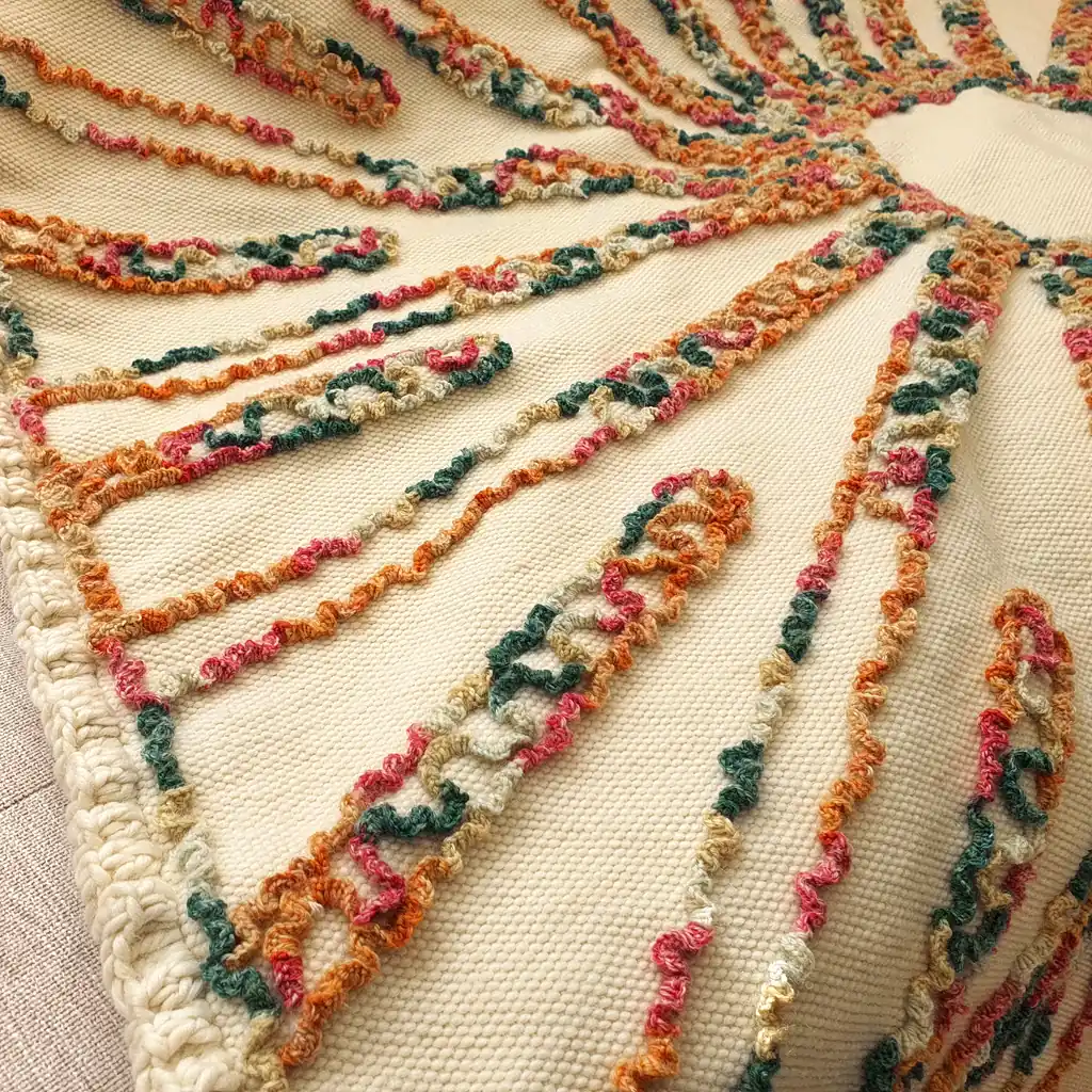 Handmade chunky knit blanket with cream and brown sunburst pattern on bed