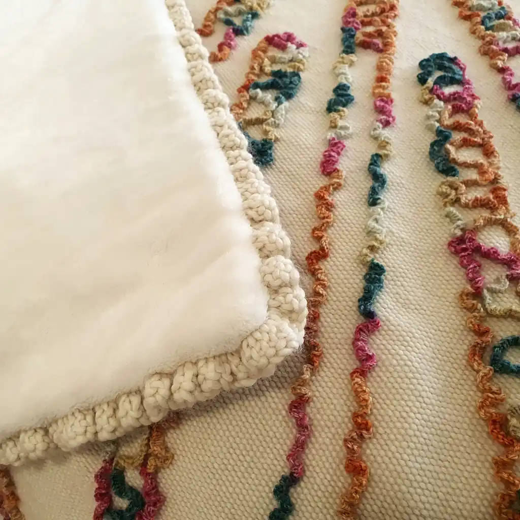 Cozy wool blanket with plush cream underside and handmade crochet border.